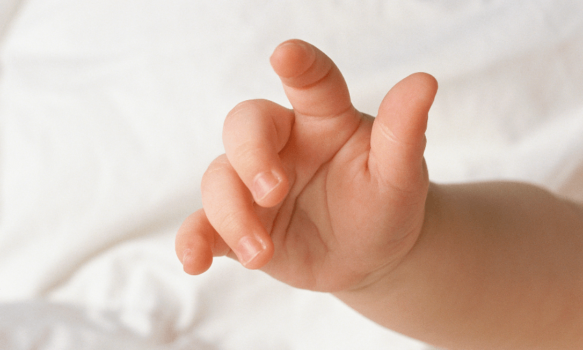 a newborn babies hand close up with a white sheet background