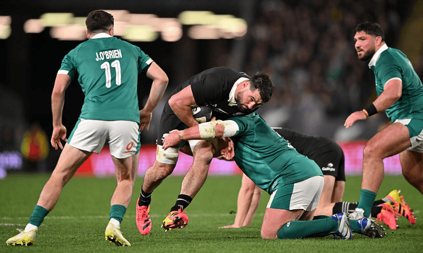 a rugby player in a black uniform is tackled by a player in a green uniform