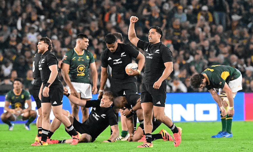 rugby players wearing black uniforms celebrate with raised fists and smiles while their opponents in Green and white look dejected