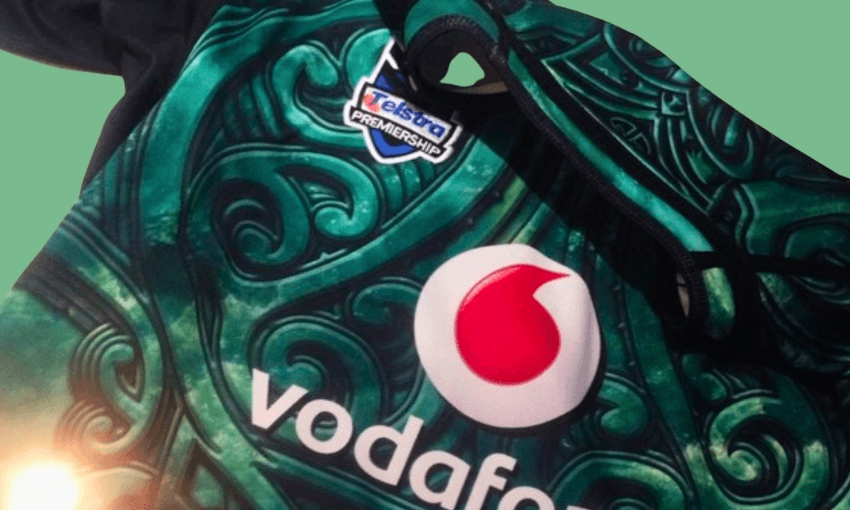 A close-up of a sports jersey with Vodafone and Telstra Premiership logos, featuring a green, swirling pattern with black trim on a pale green background.