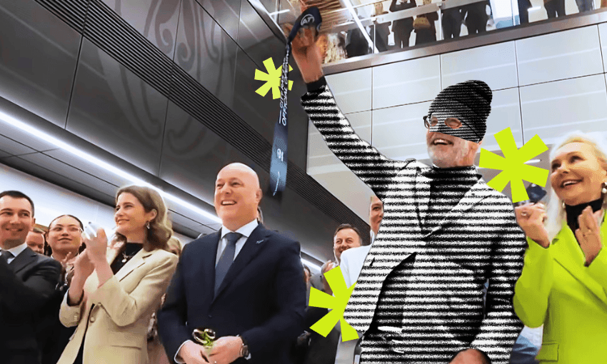 A group of people clap as a man in a striped outfit and beanie raises an object. Yellow asterisks decorate the image; the setting appears to be a modern indoor event or ceremony.