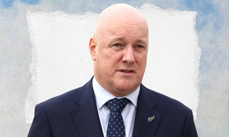 A bald man in a dark suit and polka dot tie stands in front of a torn paper background with a blue sky motif.