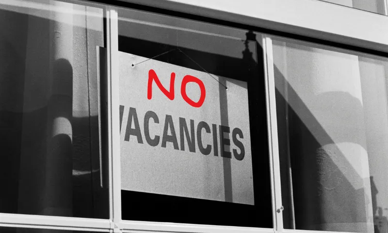 a black and white sign saying "vacancies" with the word "no" added above it in red