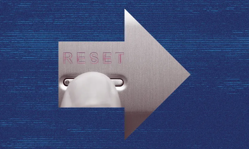 Close-up of a finger pressing a "Reset" button on a metallic surface. The image is shaped like an arrow pointing to the right, set against a textured blue background.