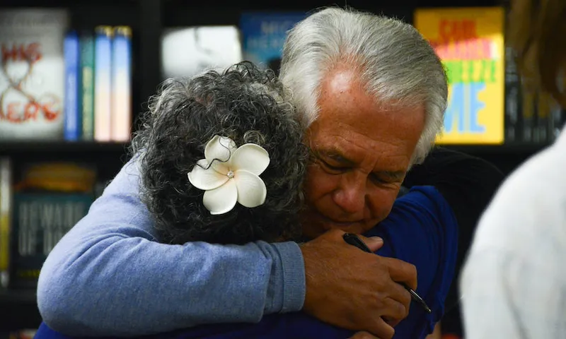 Two older people, a man and a woman, hugging in a bookstore