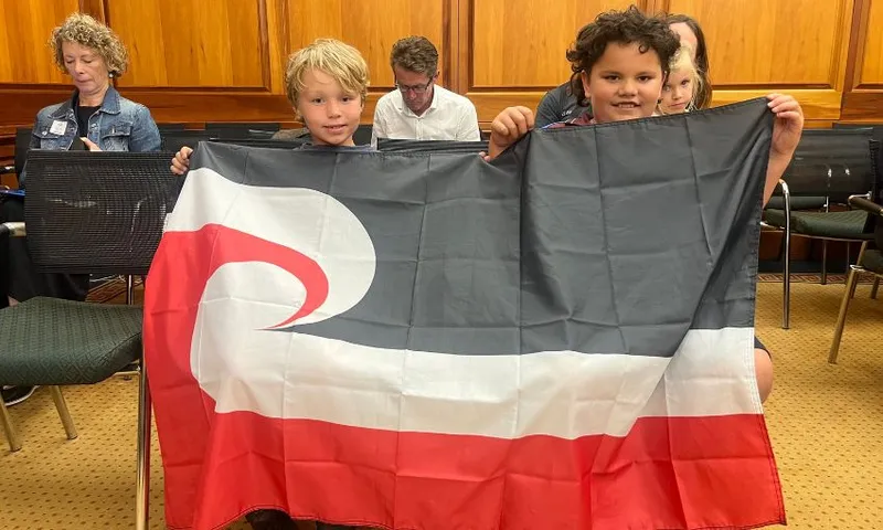 Children hold up a Tino Rangatiratanga flag.