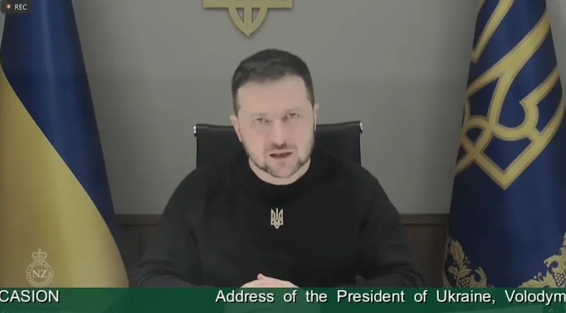 A man in a dark shirt with the parliament tickertape beneath the screenshot