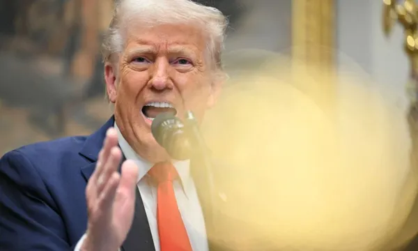 Donald Trump raises a hand as he speaks animatedly to media.