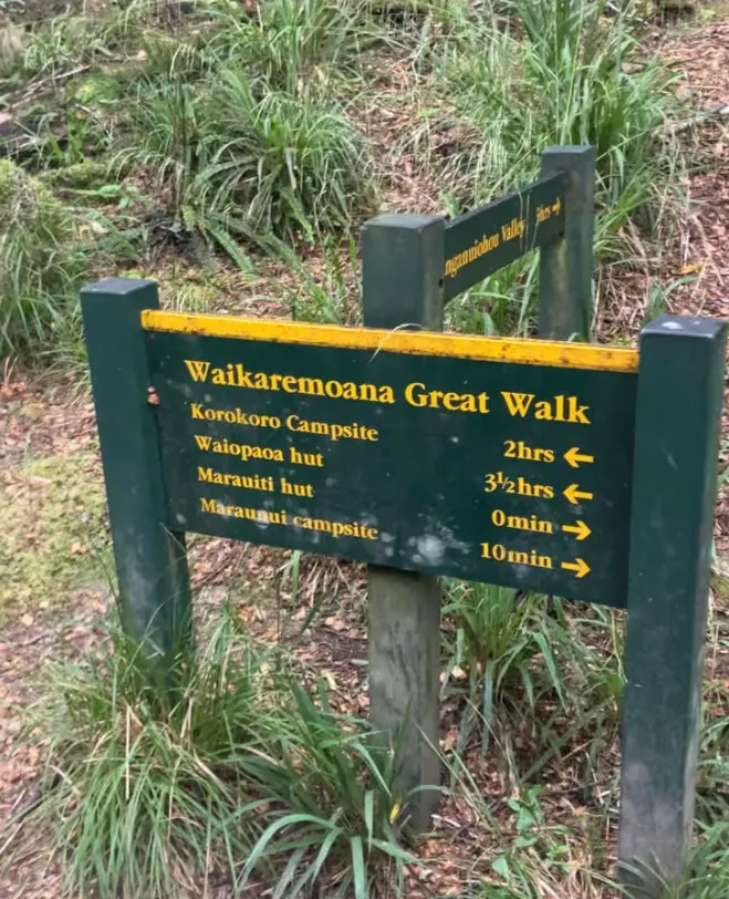 photo of a green and yellow DOC sign listing locations and walk times