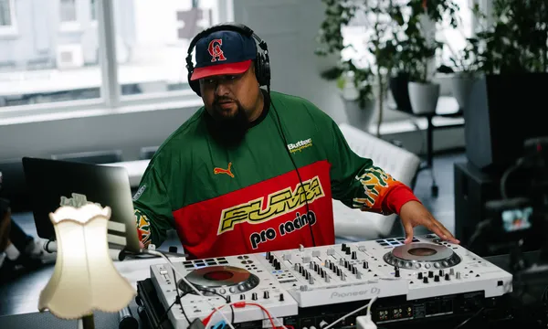 Man on a DJ deck wearing cap and headphones