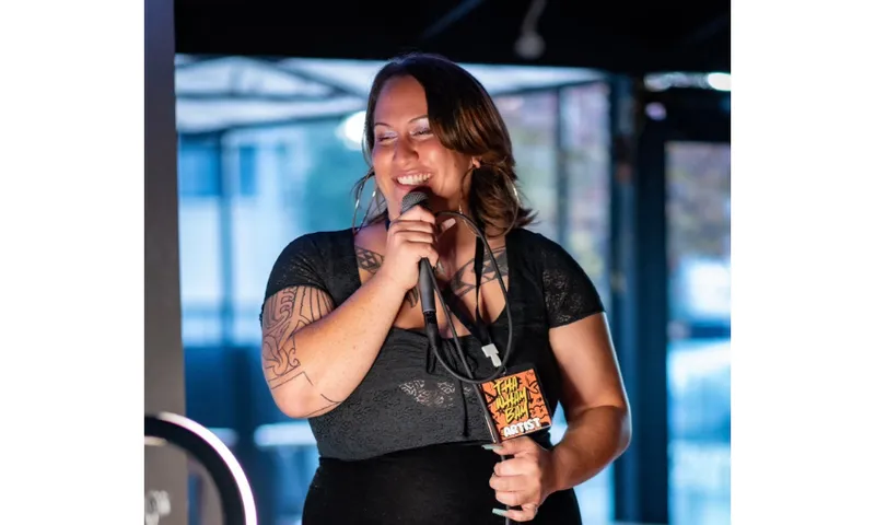 Photo of a woman holding a microphone. She is smiling.