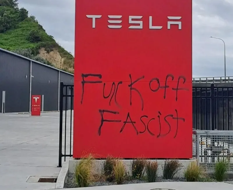 ret tesla signage with 'fuck off fascist' spray painted on in black