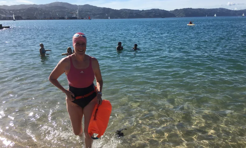 A photograph of Kate Camp walking out of the sea, smiling.