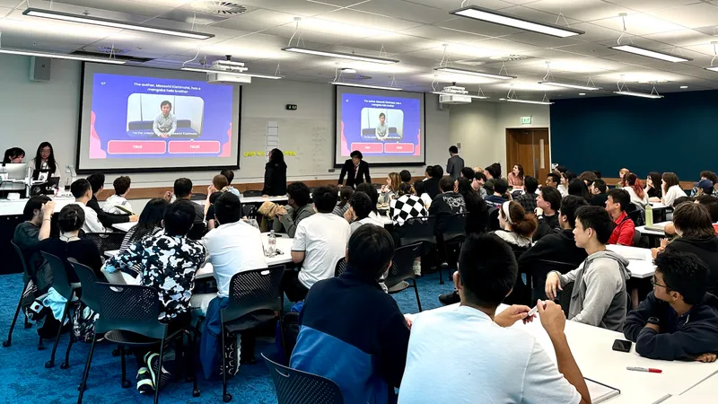 A conference room filled with people at tables, watching a presentation on two big screens