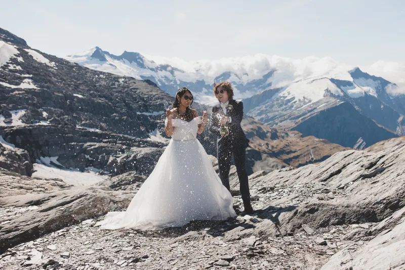 A bride and groom pose in a mountainscape