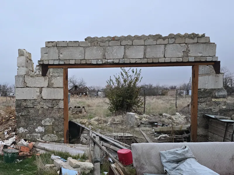 A wall of concrete blocks stands alone, surrounded by rubble
