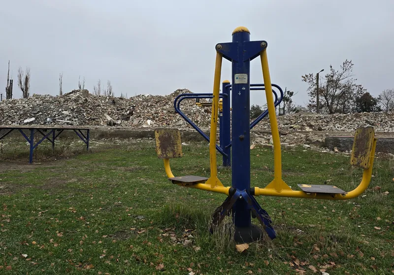 An empty playground in front of a pile of rubble
