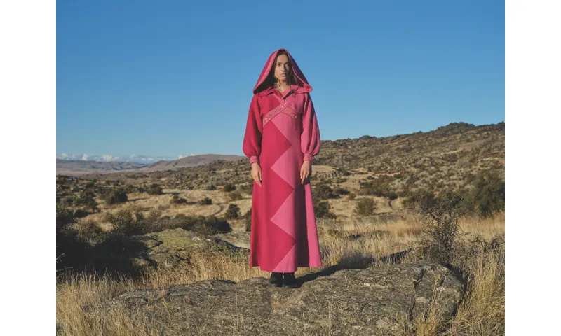 Photography of model Ngahuia Williams in bright pink garment, standing in Alexandra landscape.