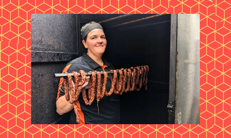 a woman with a smile holds a long string of sausages