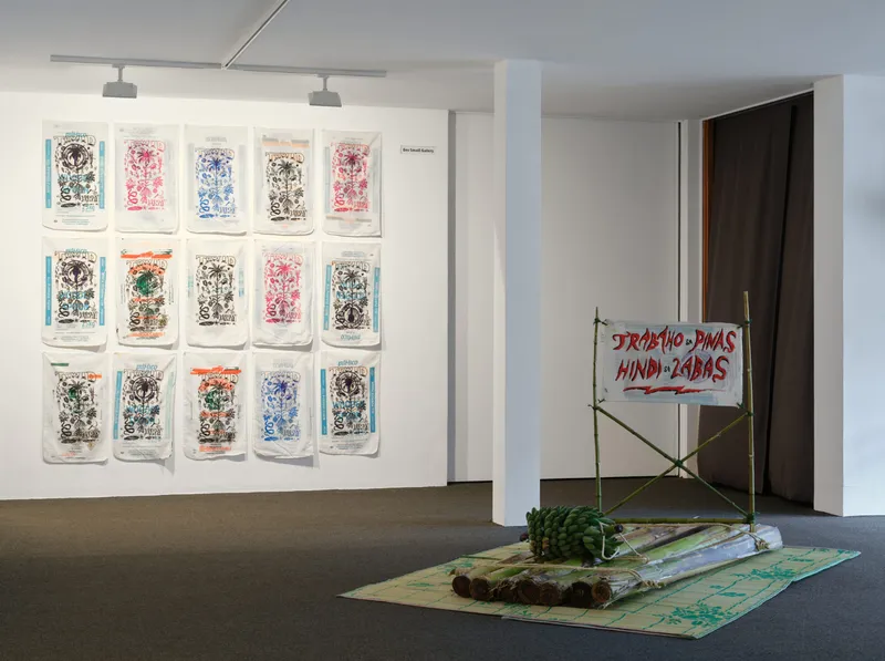 interior shot of gallery. one wall covered in screen printed posters, banana tree raft on the floor.