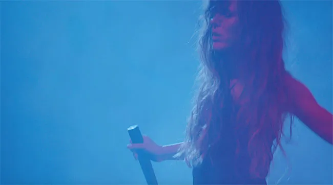 singer with long har under blue light