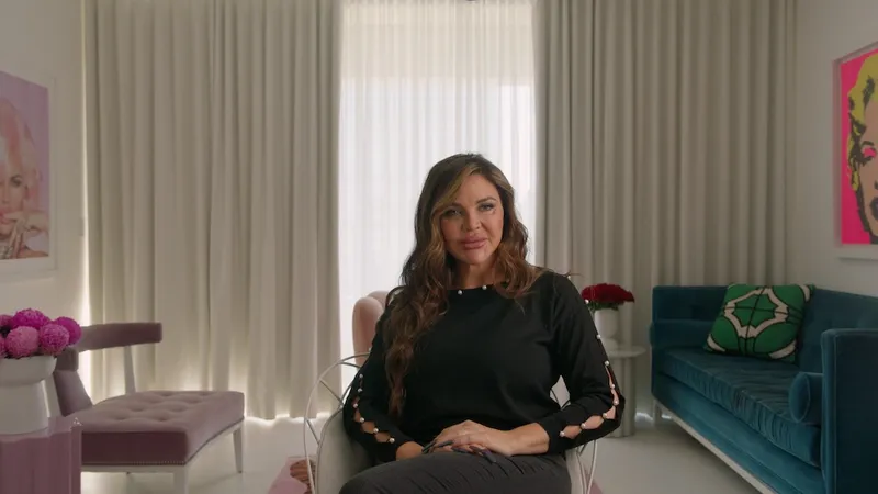 a woman in a black dress being interviewed in an apartment