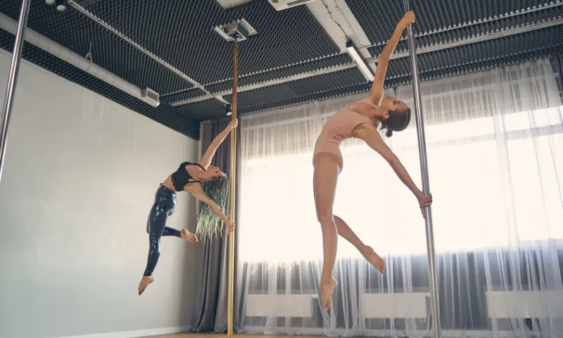 two people on poles in a fitness studio