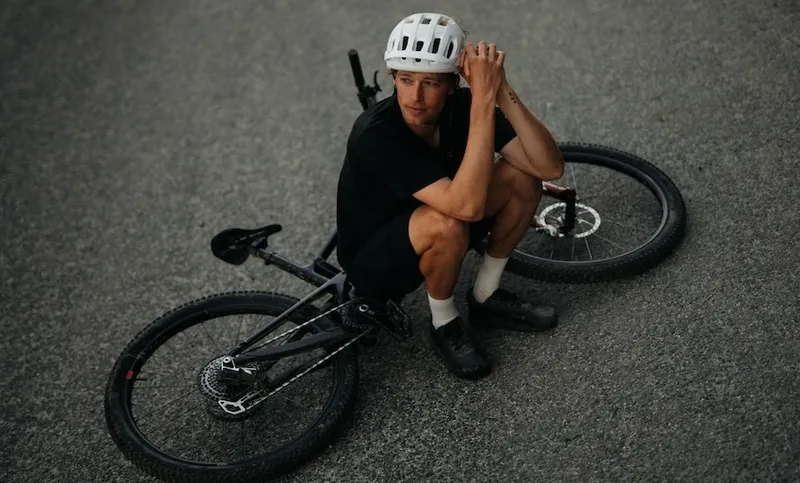 a man with a white helmet sits on his bike on grey tarmac
