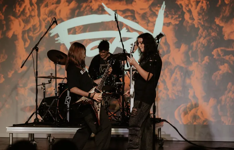 three punk teenage girls playing metal music on stage
