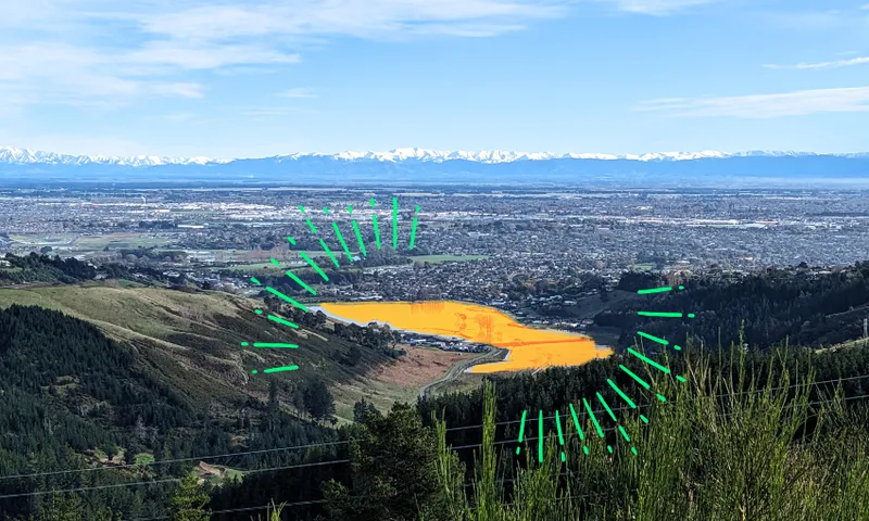 a photo of the canterbury plains with an orange flood water lake shining in the centre