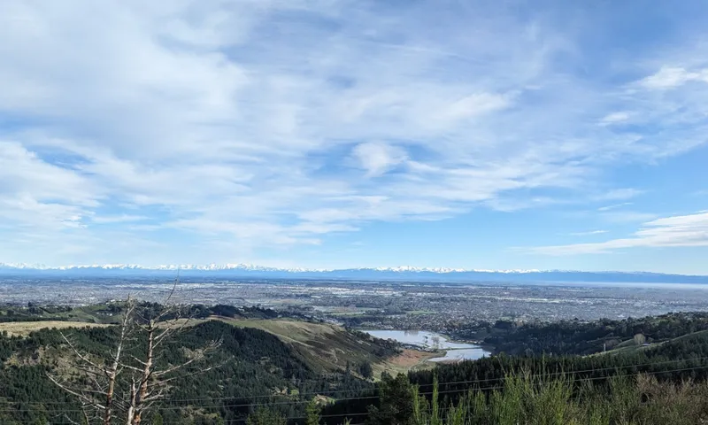 a big blue sky and a small aptch of water visible at the base of the hills below