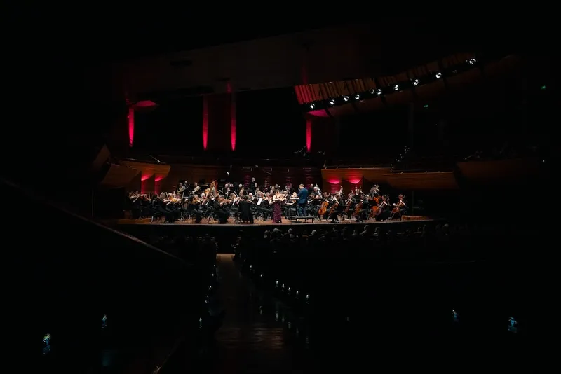 a dark concert hall with a lot of interesting instrument on an illuminated stage