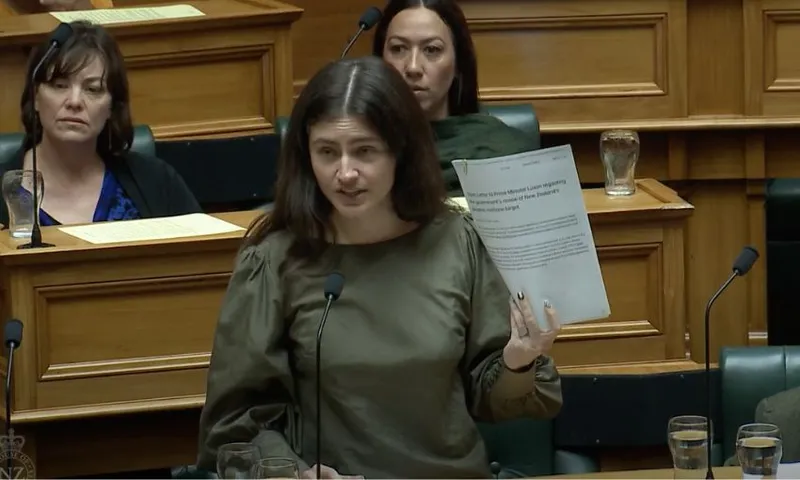 Chlöe Swarbrick, speaking in the House of Representatives, holds an open letter penned by 26 climate scientists to our government.