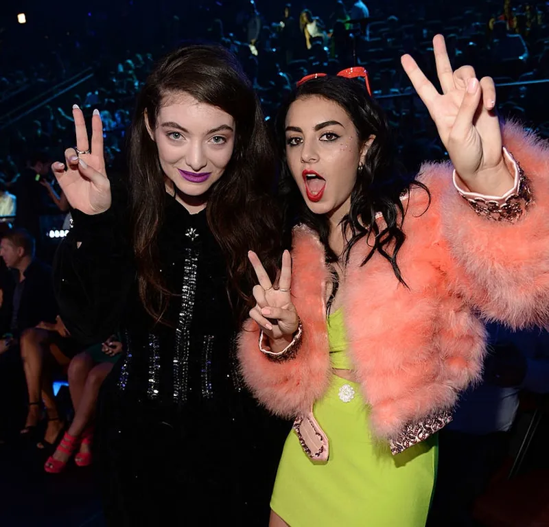 Lorde and Charli XCX attend the 2014 MTV Video Music Awards, Lorde dressed in black and Charli xcx in a peach fur jacket