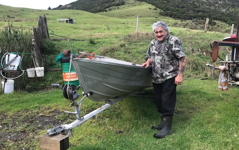 A man is smiling next to his boat.