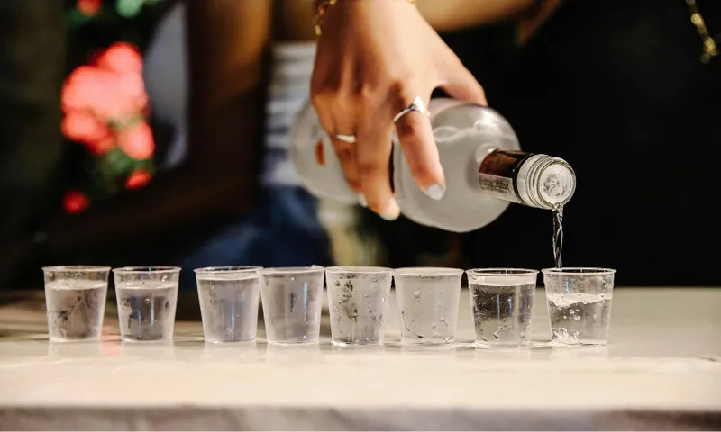 someone pouring shots from an icy vodka bottle
