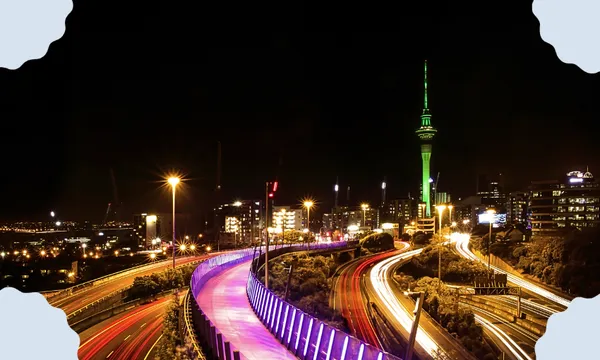 a picture of Auckland at night with the illuminated light path and the sky tower in the background
