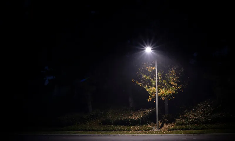 a dark street with lots of shadows and a single streetlight