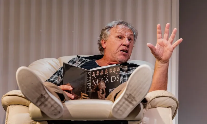 Andrew Grainger in End of Summer Time, on a lazy boy reading a colin meads book