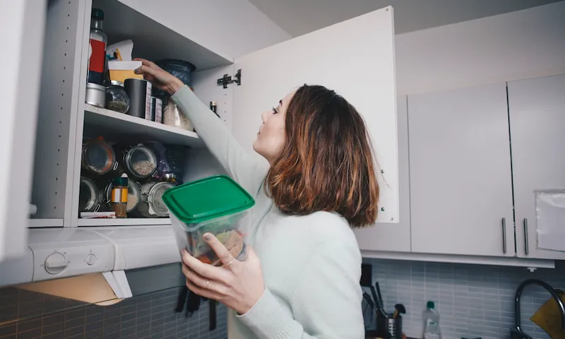 Young woman searching in cabinet at kitchen