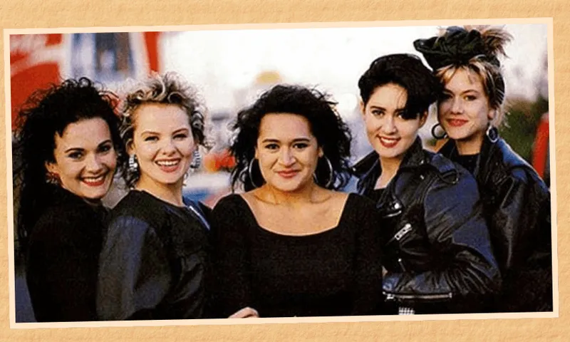 A portrait of the band When The Cat's Away, with five women wearing black and smiling at the camera