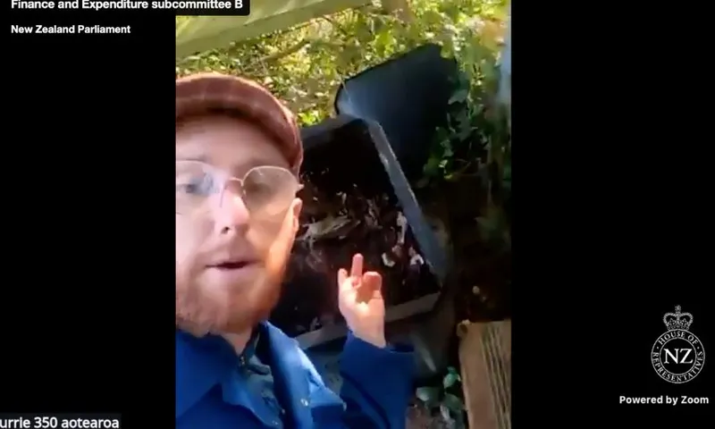 Adam Currie stands in front of, and points to, a compost heap.