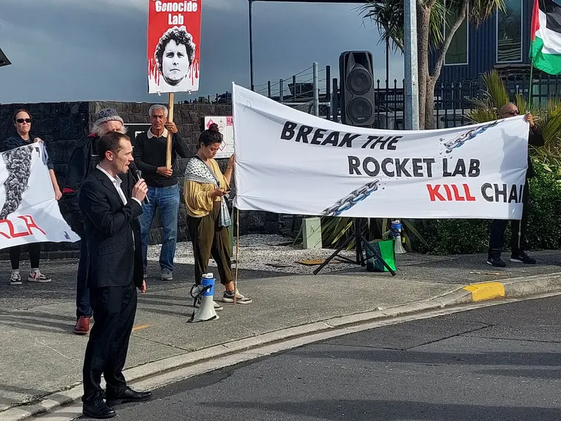 people holding hand painted signs one says 'break the rocket lab kill chain'