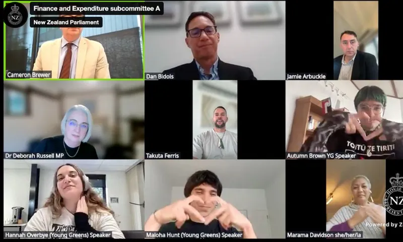 A screenshot from the livestream of the RSB hearings, showing two Young Greens members making heart-hand signs for Marama Davidson, also on screen.