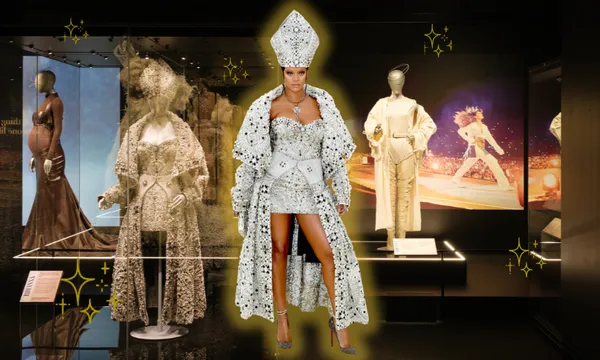 A woman in a sparkly, papal-inspired outfit (Rihanna) stands in a museum exhibit showcasing glamorous stage costumes, with bright star effects highlighting her and the mannequins.