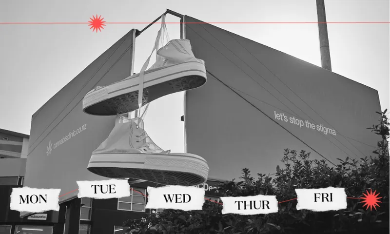 A pair of giant chuck taylor sneakers hang from two standalone billboards