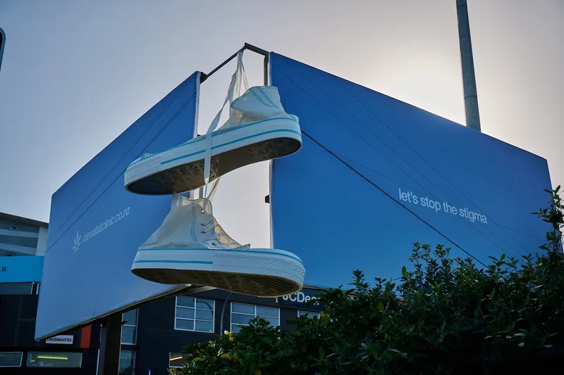 A pair of giant chuck taylor sneakers hang from two standalone billboards