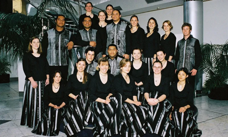 A choir portrait featuring about 20 young people of different ethnicities wearing black and silver uniforms