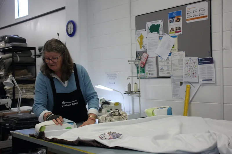 woman at a pattern cutting table in a sewing room wearing an apron