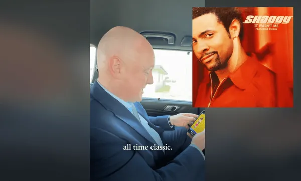 A man in a blue suit sits in a car, looking at his phone. An album cover of Shaggy's "It Wasn't Me" appears in the corner. Text at the bottom reads, "all time classic.